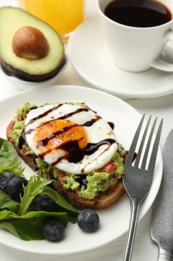 Beyaz ahşap masada servis edilen avokado tostlu sağlıklı bir kahvaltı.