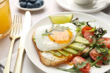 Avokado tostlu sağlıklı bir kahvaltı. Işık masasında servis edilir. Yakın plan.