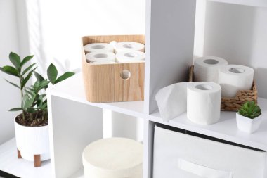 Tuvalet kağıdı ruloları ve içerideki raflarda çiçek dekoru.