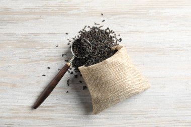 Kurumuş siyah çay yapraklı çuval bezi ve ahşap masa üzerinde kepçe, düz yatıyordu.