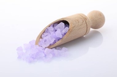 Beyaz arka planda ahşap kepçe içinde mor deniz tuzu