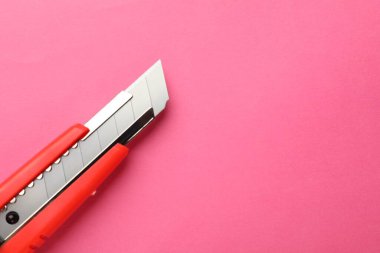 Pembe arka planda keskin bir kağıt bıçak, üst manzara. Metin için boşluk