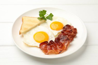 Beyaz ahşap masada servis edilen yağda yumurta ve pastırmalı nefis bir kahvaltı.