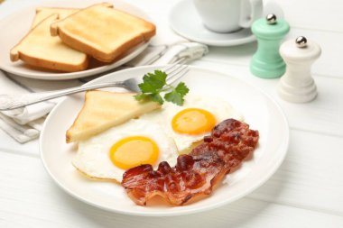 Beyaz ahşap masada servis edilen yağda yumurta ve pastırmalı nefis bir kahvaltı.