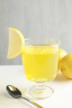 Tatlı kasesinde leziz sarı jöle ve beyaz masada limonlar, yakın plan.