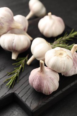 Siyah masada taze sarımsak soğanı ve biberiye, yakın plan.