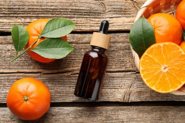 Bir şişe mandalina yağı ve ahşap masada taze meyveler.