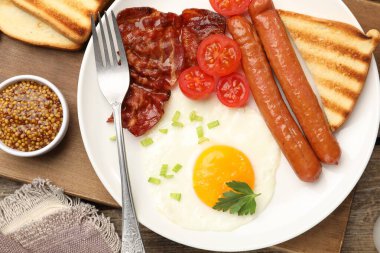 Tahta masada servis edilen kızarmış yumurta, sosis ve domuz pastırması ile nefis bir kahvaltı.
