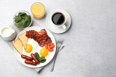 Açık gri masada servis edilen kızarmış yumurta, sosis ve domuz pastırması ile nefis bir kahvaltı. Metin için boşluk