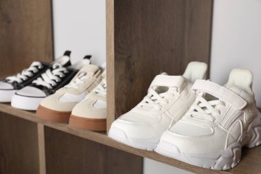 İçerideki ahşap raflarda farklı stil çocuk ayakkabıları, yakın plan.