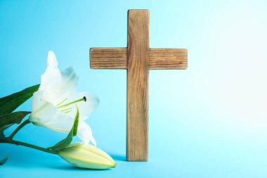 Paskalya. Ahşap haç ve açık mavi arka planda güzel zambak çiçekleri, yakın plan.