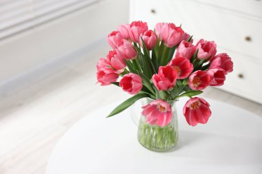 Beyaz masadaki vazoda duran pembe laleler. Metin için boşluk