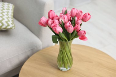 İçerideki ahşap masada vazoda pembe laleler.