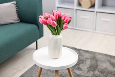 Beyaz masadaki vazodaki güzel pembe laleler.