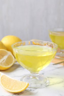 Tatlı kasesinde leziz sarı jöle ve beyaz mermer masada taze limonlar, yakın plan.