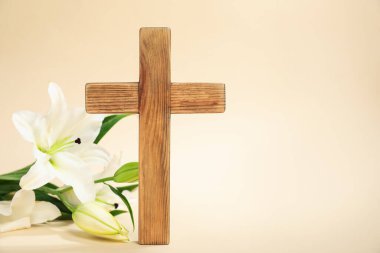 Paskalya. Ahşap haç ve bej arka planda güzel zambak çiçekleri, metin için boşluk ile yakın plan