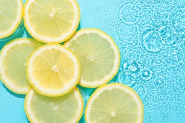 Açık mavi arka planda limon dilimleri, düz. Metin için boşluk