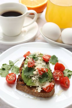 Beyaz masada servis edilen lezzetli avokado tostlu sağlıklı bir kahvaltı.