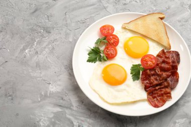 Yağda yumurta ve pastırmalı leziz kahvaltı, dokulu gri masada servis edilir. Metin için boşluk
