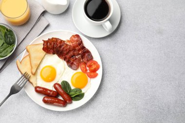 Açık gri masada servis edilen kızarmış yumurta, sosis ve domuz pastırması ile nefis bir kahvaltı. Metin için boşluk