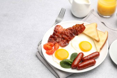 Açık gri masada servis edilen kızarmış yumurta, sosis ve pastırma ile nefis bir kahvaltı. Metin için boşluk