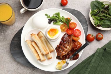 Gri masada servis edilen kaynamış yumurta ve pastırmalı lezzetli bir kahvaltı.