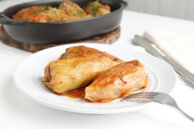 Beyaz masada servis edilen lezzetli lahana dürümleri, yakın plan.