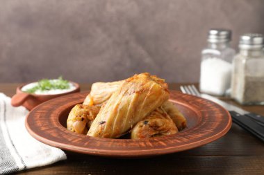 Ahşap masada servis edilen lezzetli lahana dürümleri, yakın plan. Metin için boşluk