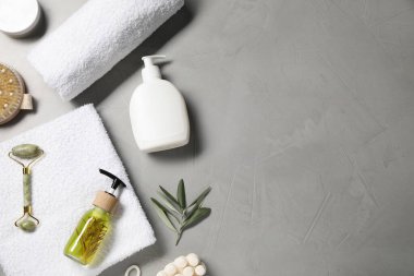 Temiz havlular ve gri arka planda kişisel bakım ürünleri. Metin için boşluk