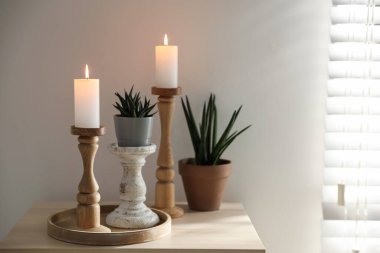 Zarif şamdanlar yanan mumlar ve ev bitkileri kapalı bir masa üzerinde, metin için yer var.