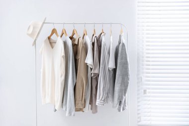 Farklı tarz kıyafetler ve askıda asılı duran şapkalar.