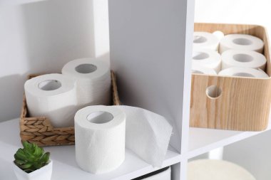 Tuvalet kağıdı ruloları ve raflardaki çiçek dekoru kapalı, yakın plan.