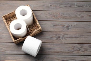 Hasır sepetin içindeki tuvalet kağıdı ruloları ahşap masanın üstünde, düz yerde. Metin için boşluk
