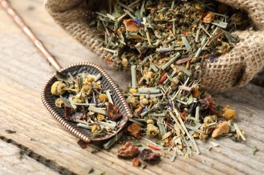 Çuvalda kurutulmuş bitki çayı ve ahşap masada metal spatula, yakın plan.