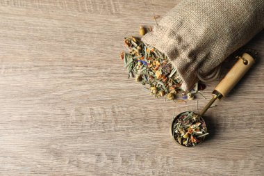 Çuvalda kurutulmuş bitki çayı yaprakları ve ahşap masada kepçe, üst manzara. Metin için boşluk