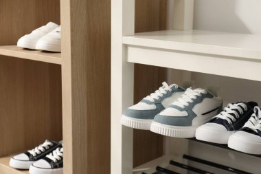 Raf ünitesinde farklı stil çocuk ayakkabıları var. Kapalı, yakın çekim.