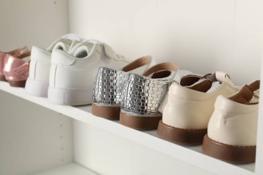 İçerideki raflarda farklı tarz çocuk ayakkabıları, yakın plan.