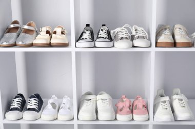 Raf ünitesinde farklı stil çocuk ayakkabıları var. Kapalı, yakın çekim.