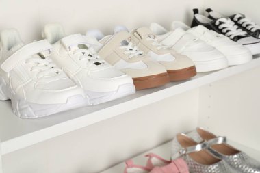 Raf ünitesinde farklı stil çocuk ayakkabıları var. Kapalı, yakın çekim.