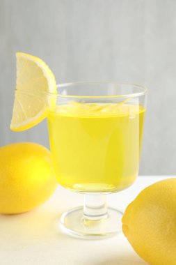 Tatlı kasesinde leziz sarı jöle ve beyaz masada limonlar, yakın plan.