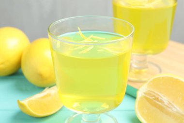 Tatlı kaselerinde leziz sarı jöle ve açık mavi ahşap masada limonlar, yakın plan.