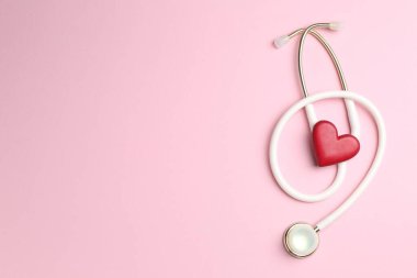 Kan basıncını ölçüyorum. Pembe arka planda steteskop ve kırmızı kalp figürü. Metin için boşluk