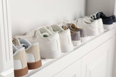 Beyaz raflarda farklı tarz çocuk ayakkabıları, yakın plan.