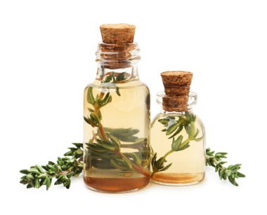 Kekik yağı şişeleri ve taze bitkiler beyaza izole edilmiş.