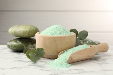 Kasedeki yeşil deniz tuzu, taşlar ve okaliptüs yaprakları beyaz mermer masada, yakın plan.