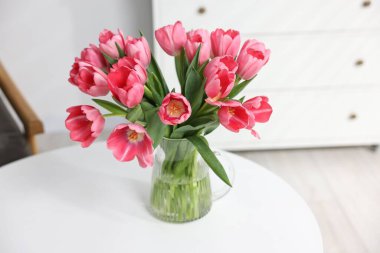 Beyaz masadaki vazoda duran pembe laleler.