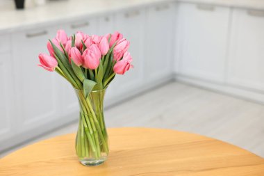 İçerideki ahşap masada vazoda pembe laleler, yakın plan. Metin için boşluk