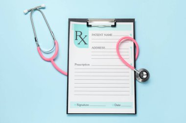 Açık mavi zemin üzerinde hastanın formunun olduğu stetoskop ve pano, düz uzanma