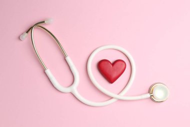 Kan basıncını ölçüyorum. Pembe arka planda steteskop ve kırmızı kalp figürü.
