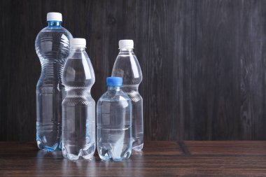 Ahşap masada farklı boyutlarda su şişeleri, metin için yer